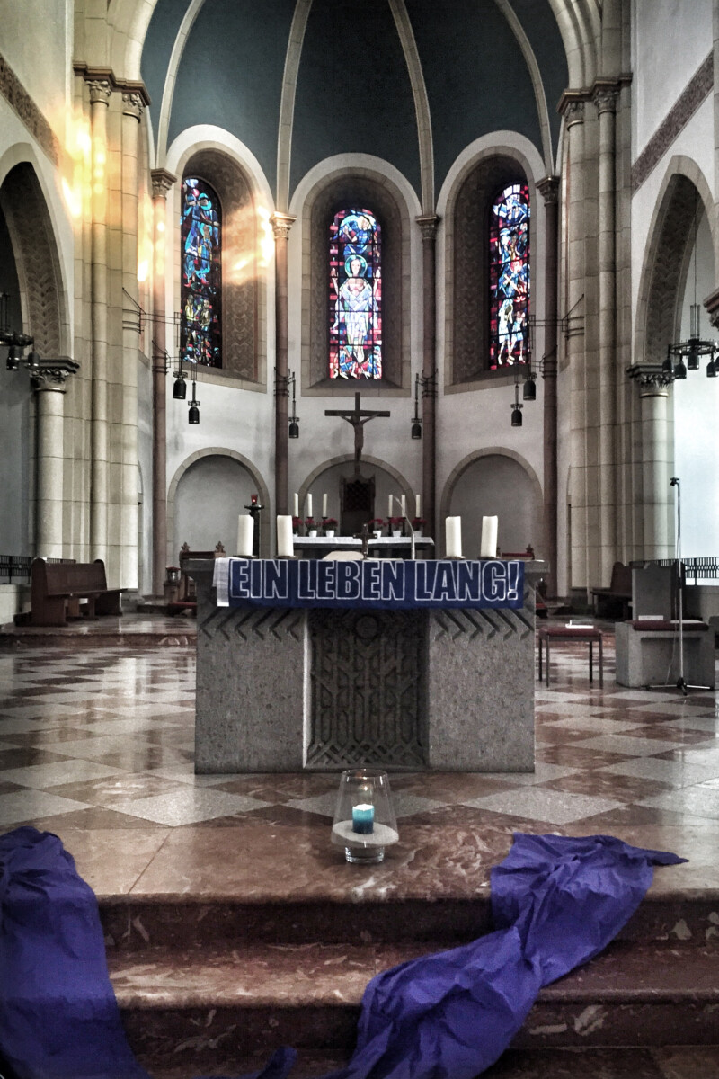 Am Altar der St.-Joseph-Kirche hängt ein blauer Schal mit dem Schriftzug "Ein Leben lang" in weißen Lettern.
