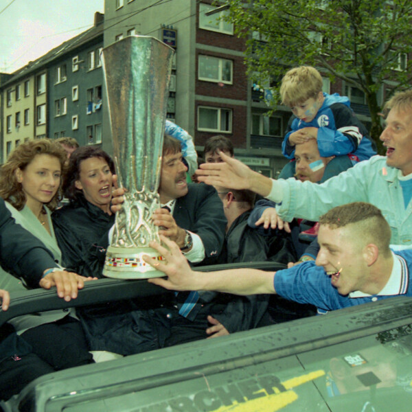 Fans des FC Schalke 04 versuchen den UEFA-Pokal zu berühren. Die Schalker Mannschaft fährt mit ihm im Cabrio über die Schalker Meile.