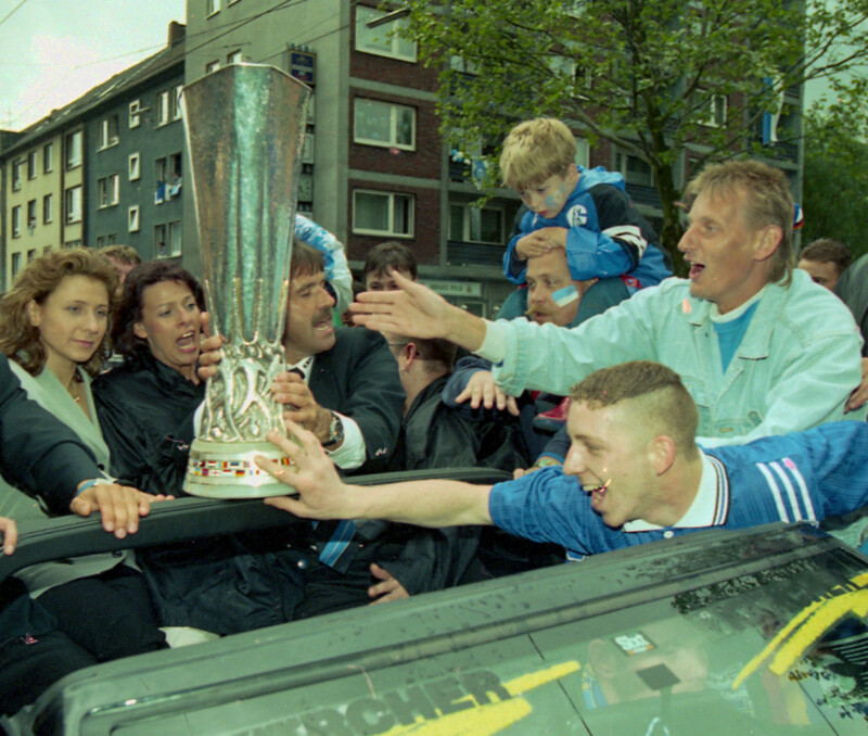 Fans des FC Schalke 04 versuchen den UEFA-Pokal zu berühren. Die Schalker Mannschaft fährt mit ihm im Cabrio über die Schalker Meile.