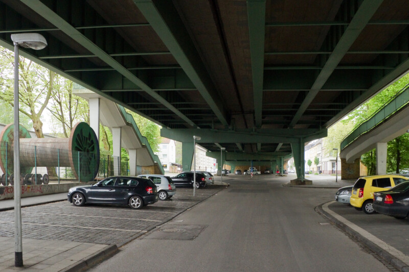 Unteransicht der Berliner Brücke. Unter ihren Stahlträgern liegen Parkplätze.