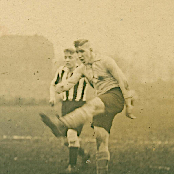 Der junge Ernst Kuzorra schießt den Ball in einem vollen Stadion. Hinter ihm steht ein Gegenspieler.