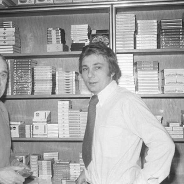 Ernst Kuzorra und Stan Libuda stehen gemeinsam vor einem Regal mit Tabakwaren und gucken in die Kamera.