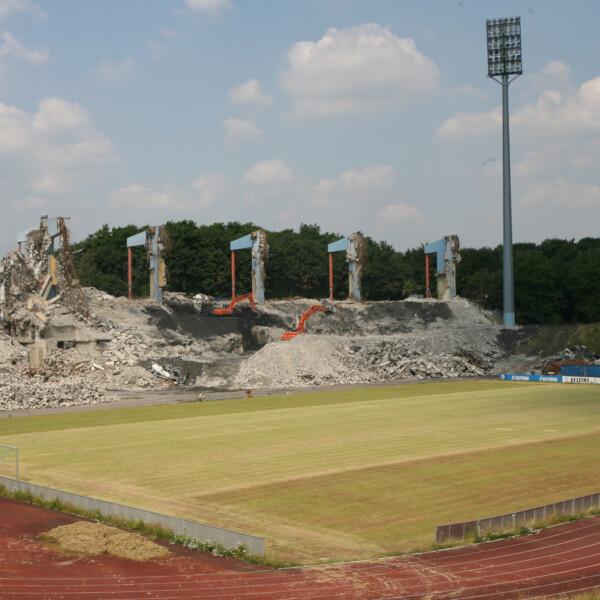 Bagger und anderes schweres Gerät demolieren die Tribüne des alten Parkstadions in Gelsenkirchen. Die Ränge rundherum sind nur noch grasbewachsene Hänge.