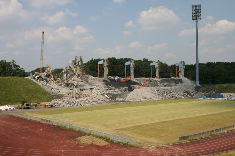 Bagger und anderes schweres Gerät demolieren die Tribüne des alten Parkstadions in Gelsenkirchen. Die Ränge rundherum sind nur noch grasbewachsene Hänge.