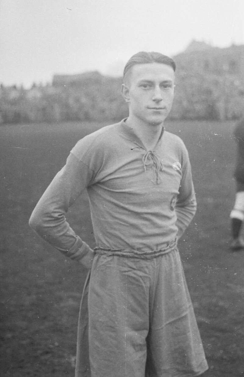 Hermann Eppenhoff steht als junger Spieler auf dem Feld eines Stadions. Die Zuschauerränge im Hintergrund sind voller Menschen.